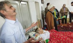 پرچم متبرک شده حرم مطهر رضوی بر بالین پاکبان بیمار گوگانی